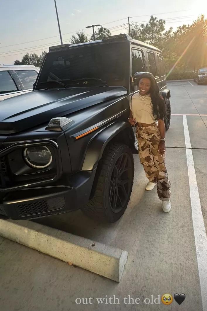 Simone Biles posing next to a car