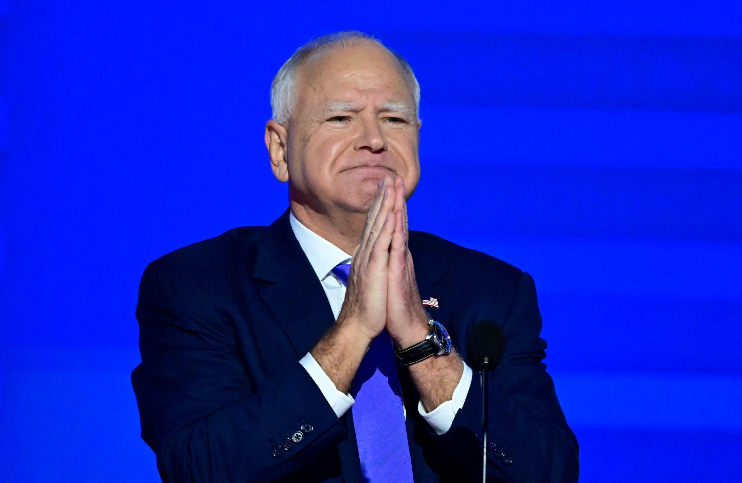 Tim Walz making a prayer gesture on stage