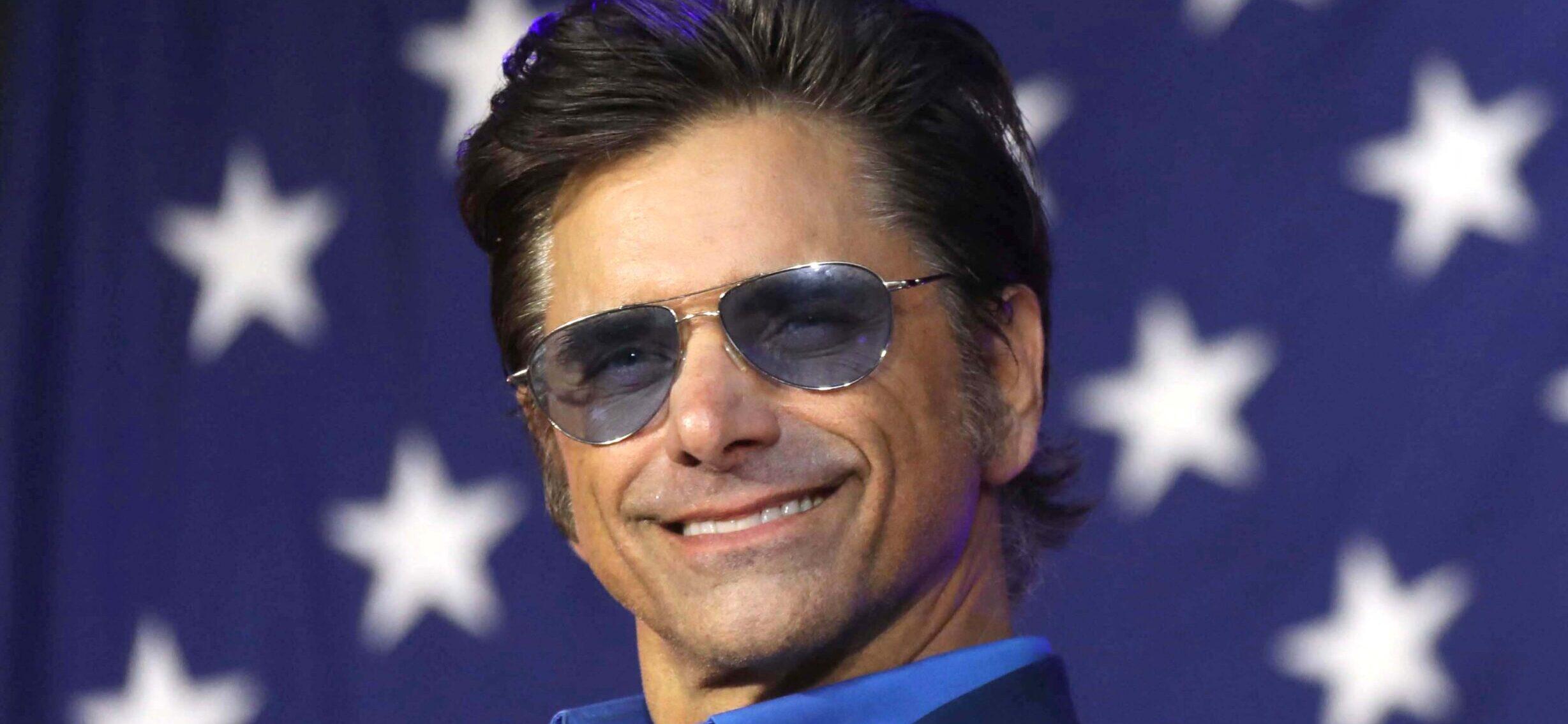 John Stamos stands in front of American flag