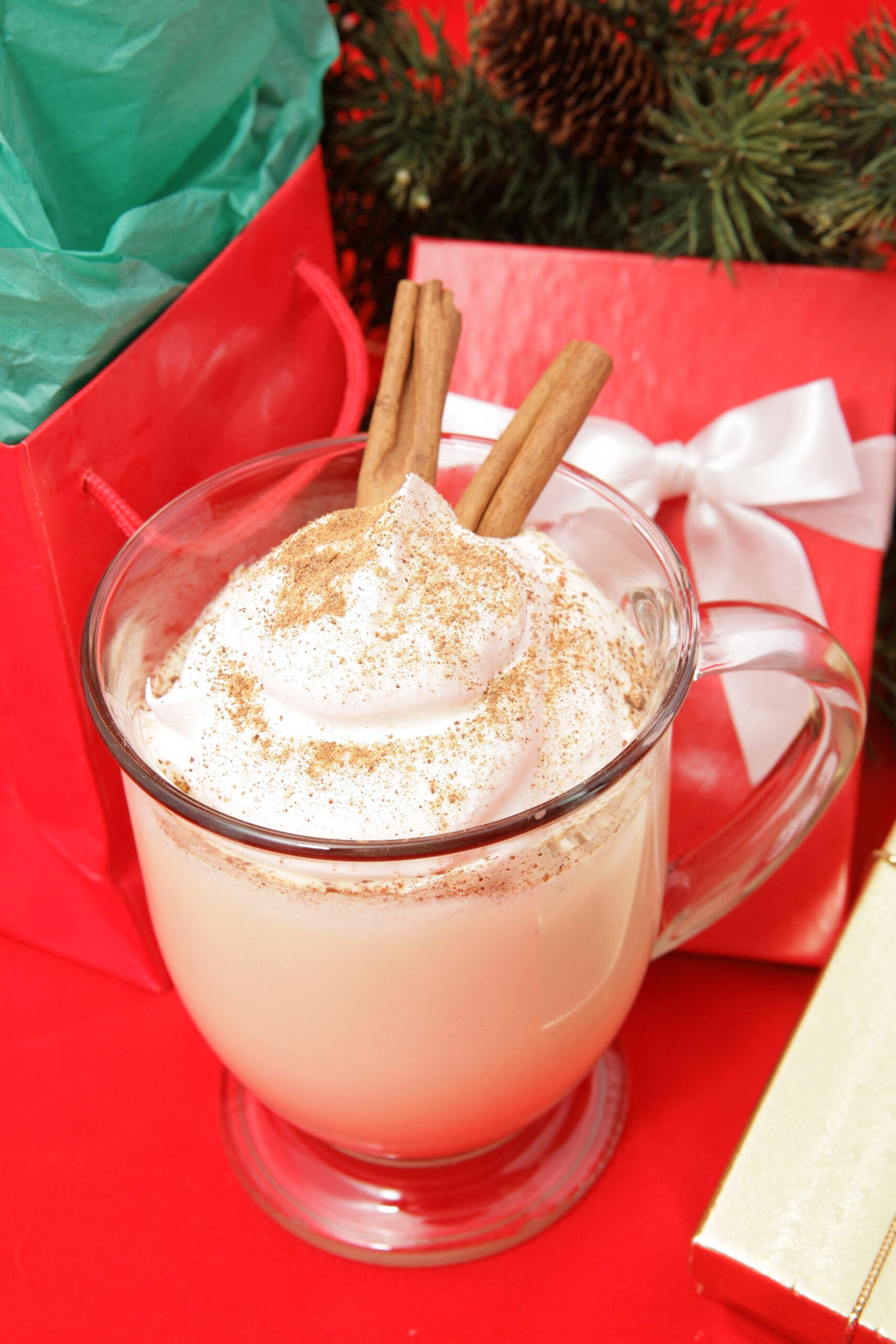 Delicious creamy eggnog on red with Christmas presents.