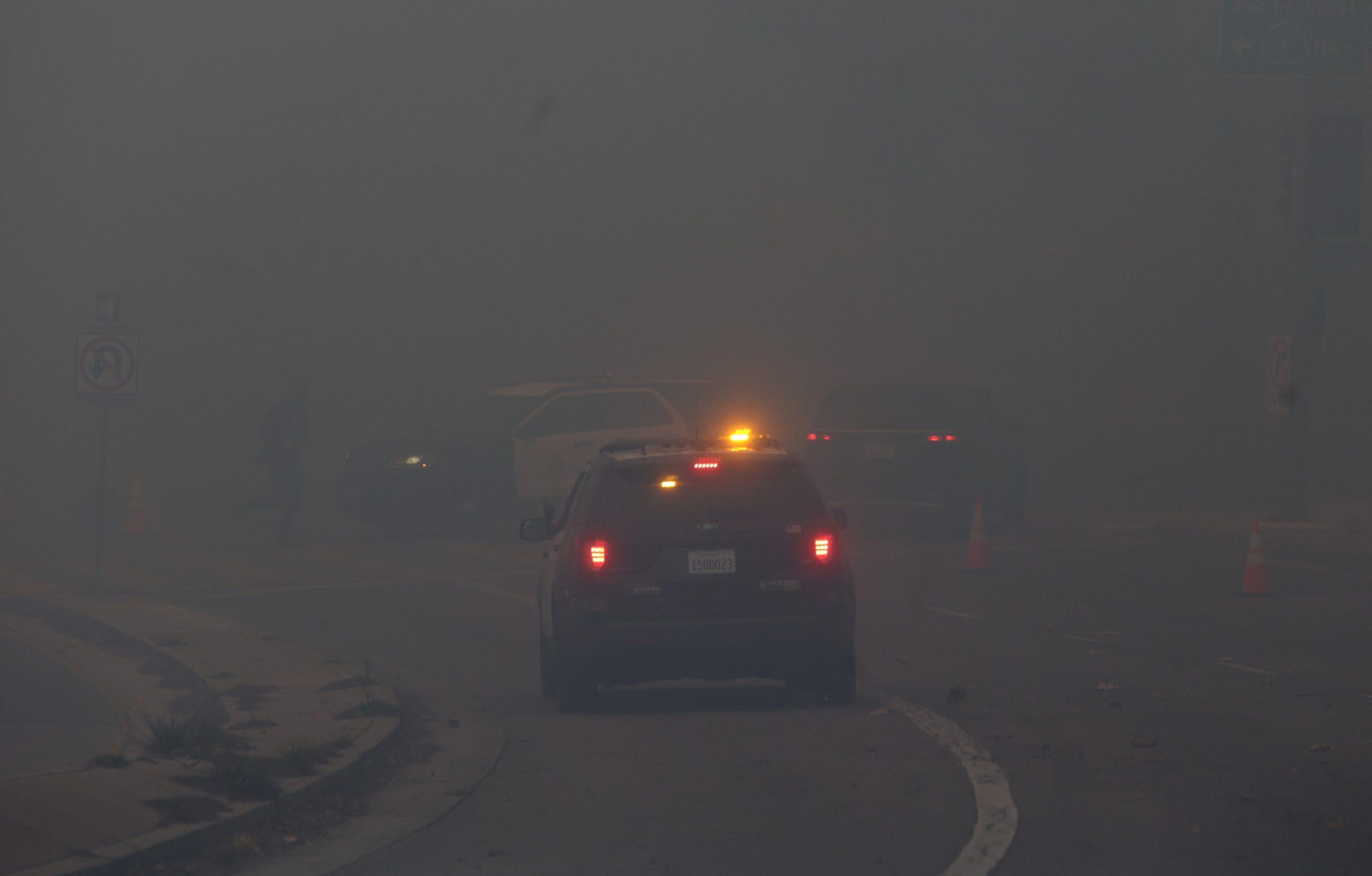 Police car driving during Pacific Palisades fire as it consumes residents homes and neighborhoods