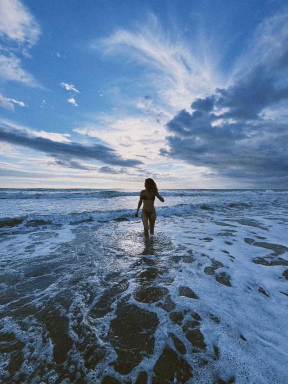 Lily James standing on the beach.