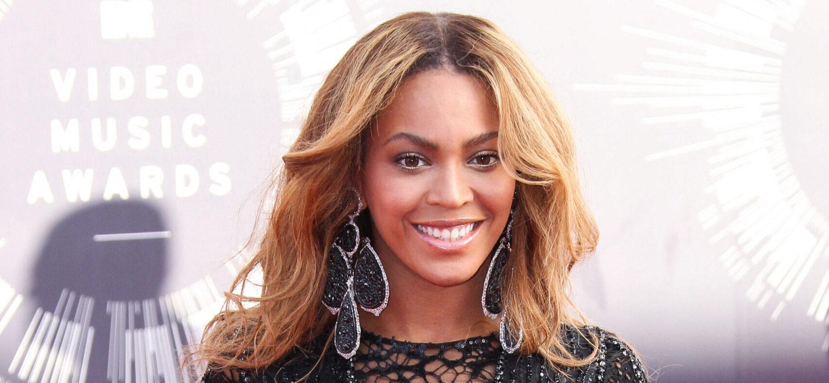 Beyoncé posing in a black dress on the red carpet.