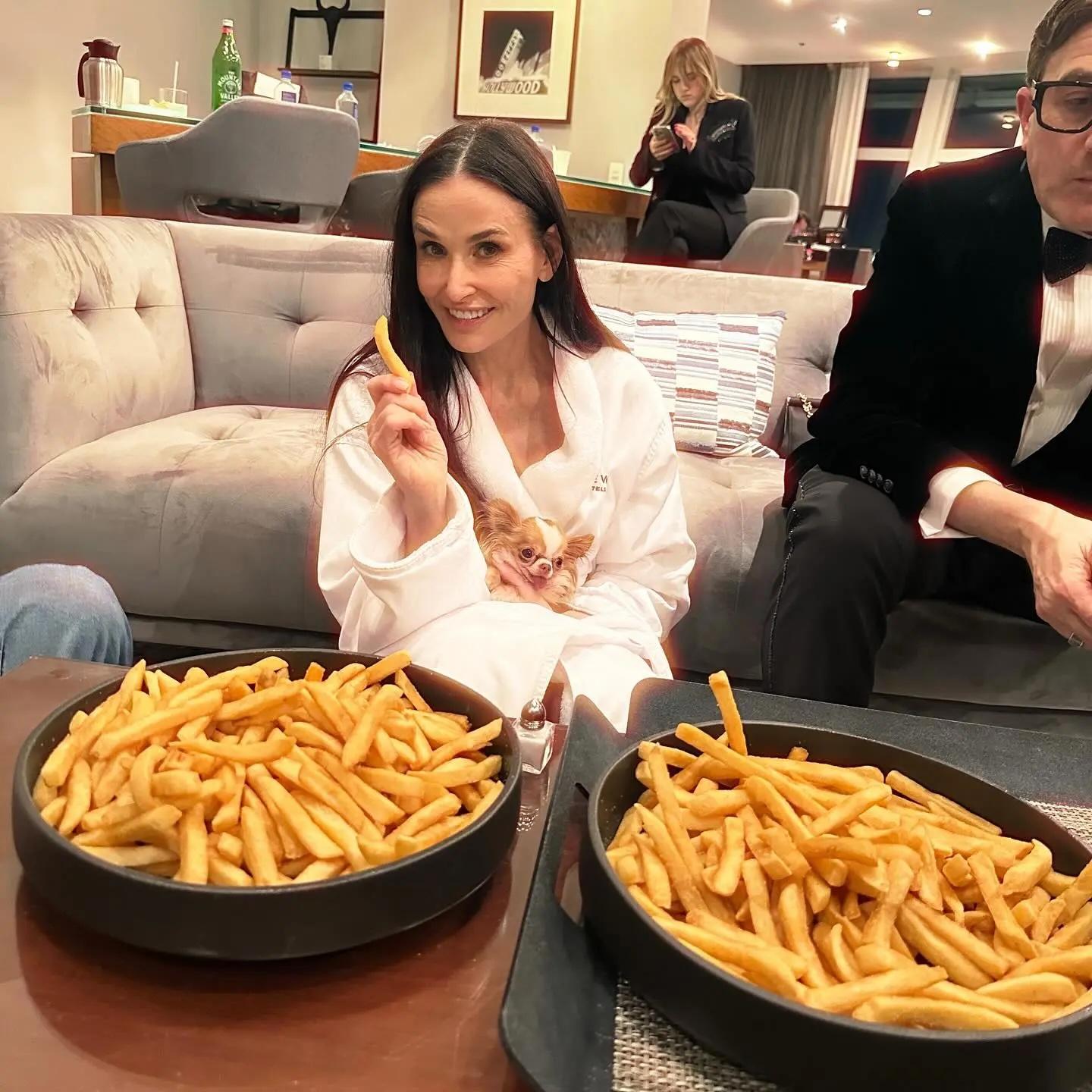 Demi Moore sitting with bowls of french fries