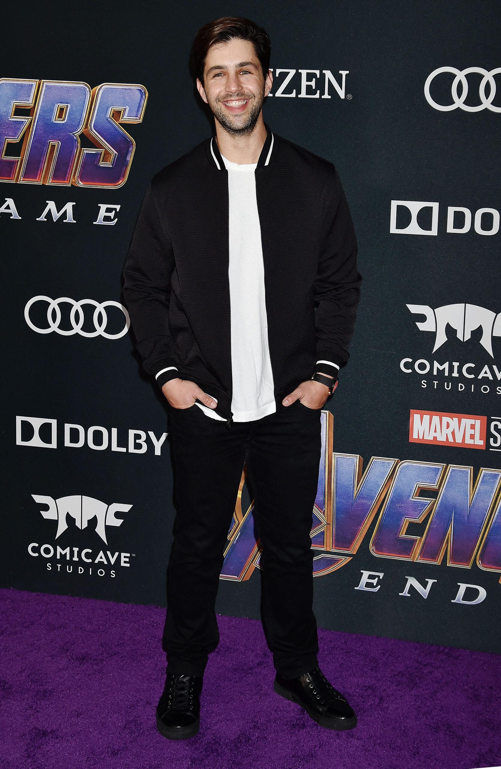 Josh Peck posing in all back on the purple carpet. 