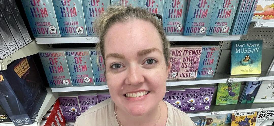 Colleen Hoover smiling in front of books