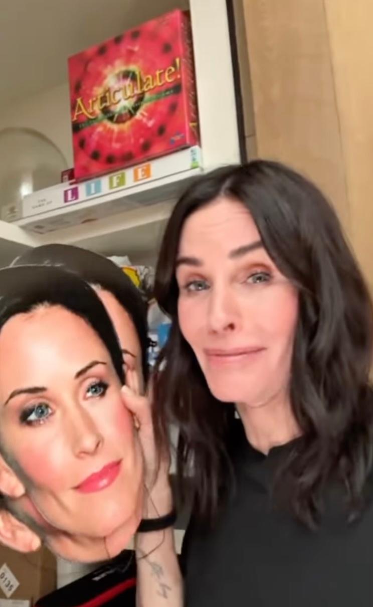 Courteney Cox holding cut outs of her face