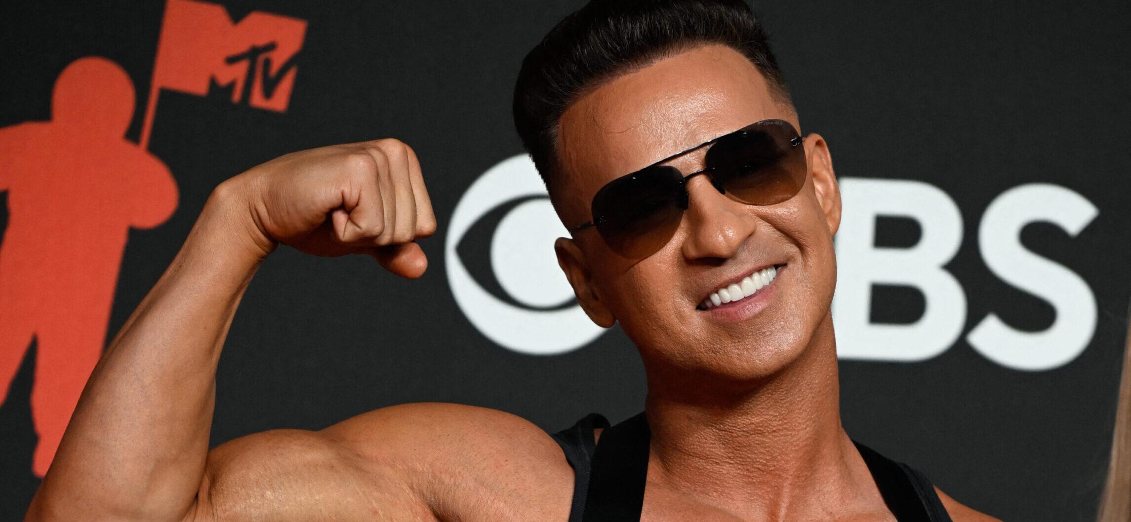Mike "The Situation" Sorrentino posing with his biceps on the red carpet.