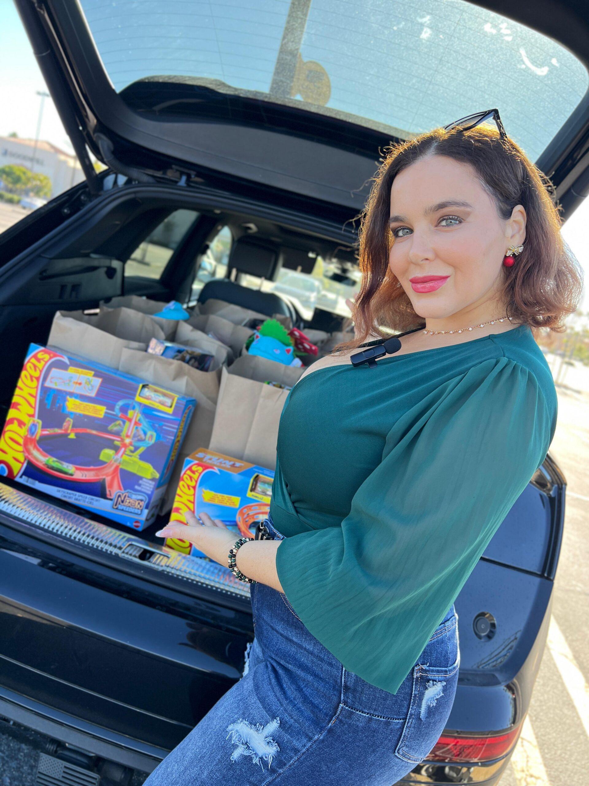 Natasha showing off toys in the trunk of a car