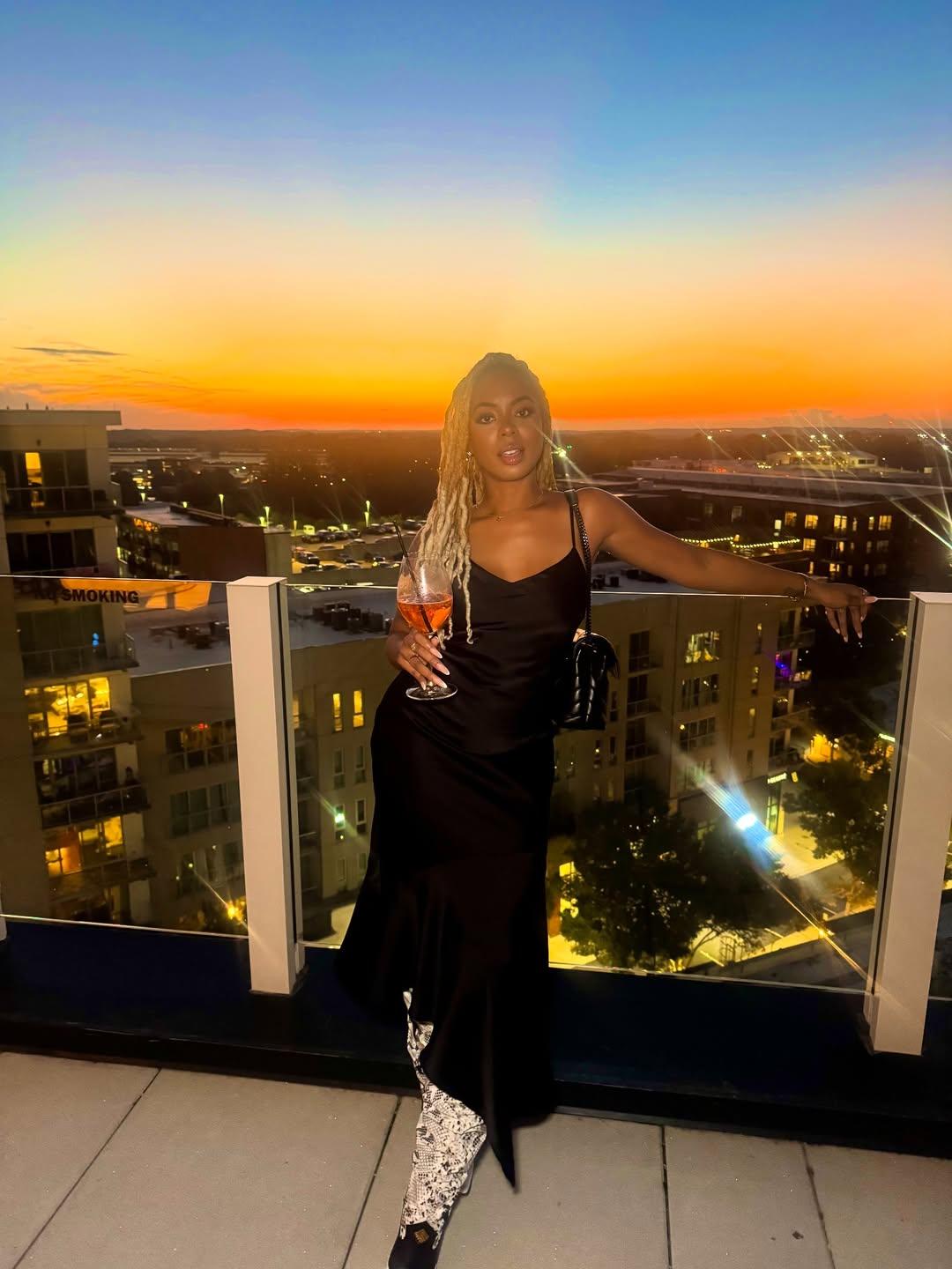 Mickey Lee posando em frente ao pôr do sol em um bar na cobertura