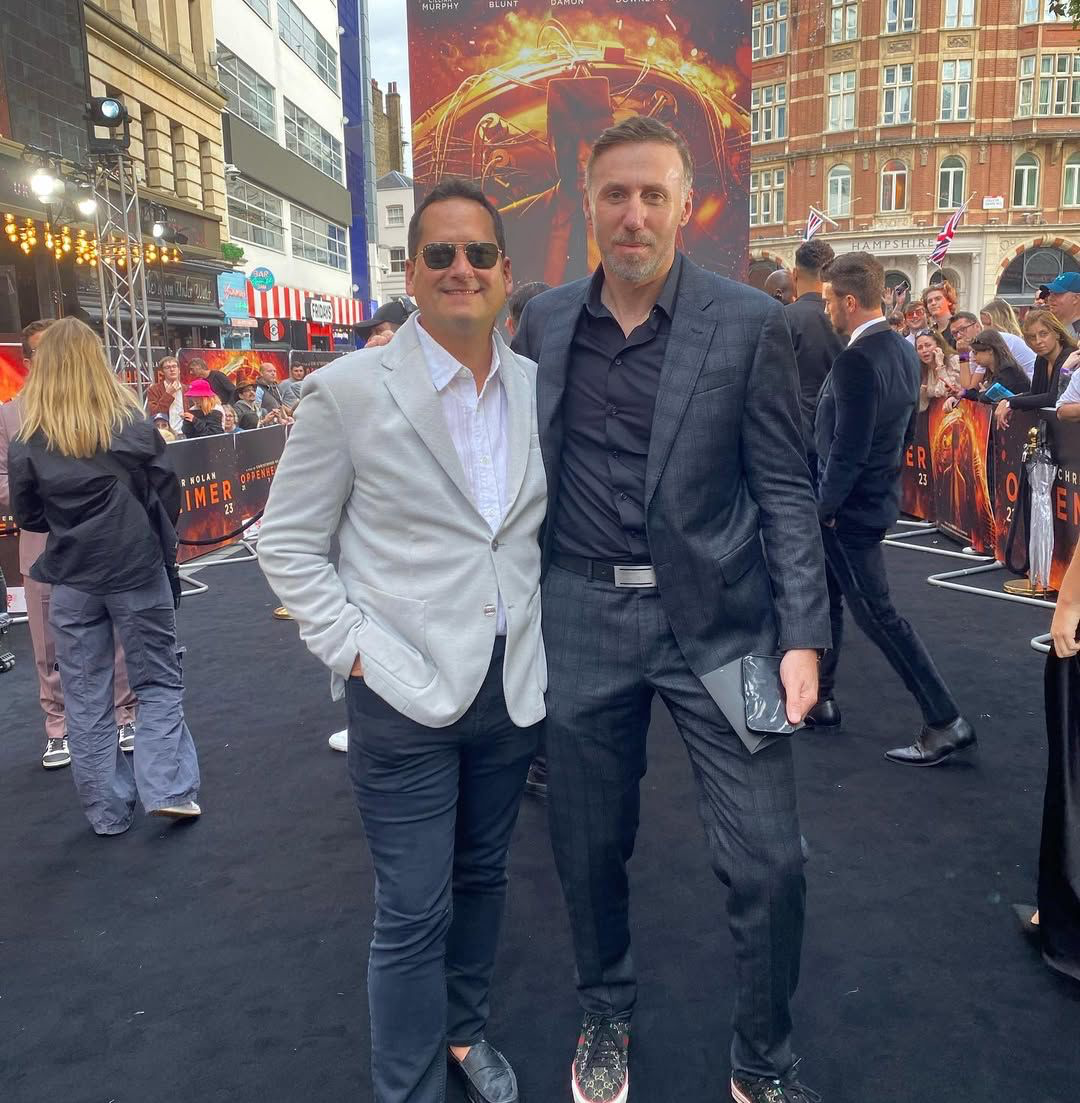 Two men standing in suits in busy city scene