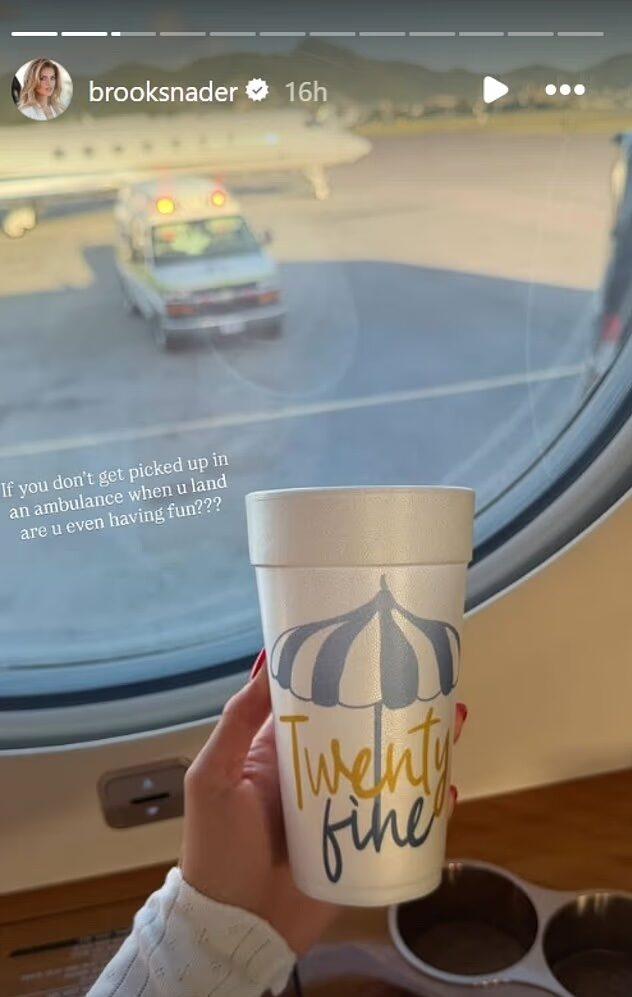 Brooks Nader holding a drink on a plane