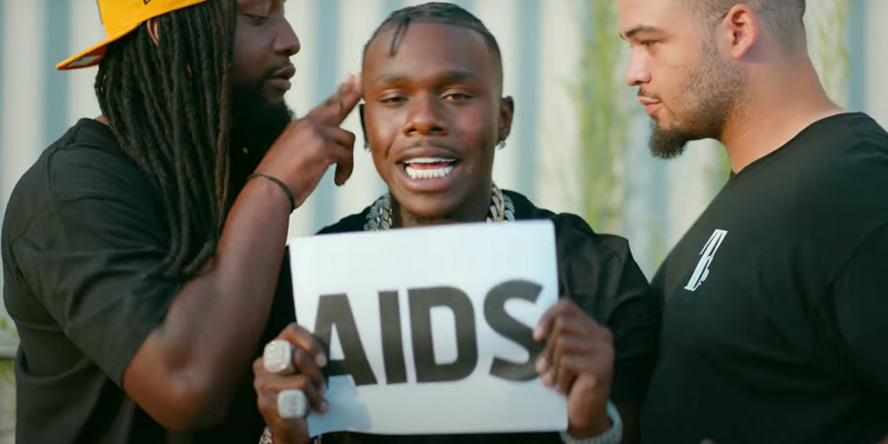 DaBaby holding up a sign that says AIDS