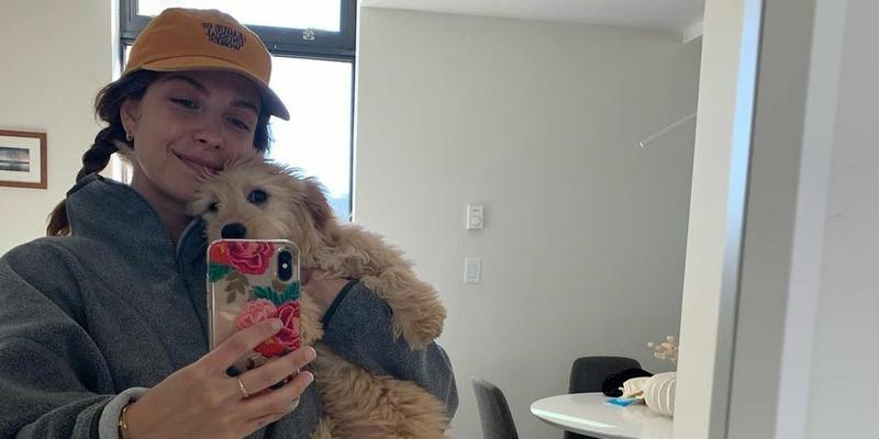 A photo showing Paige Spara in casual clothes, taking a selfie with her furry friend.