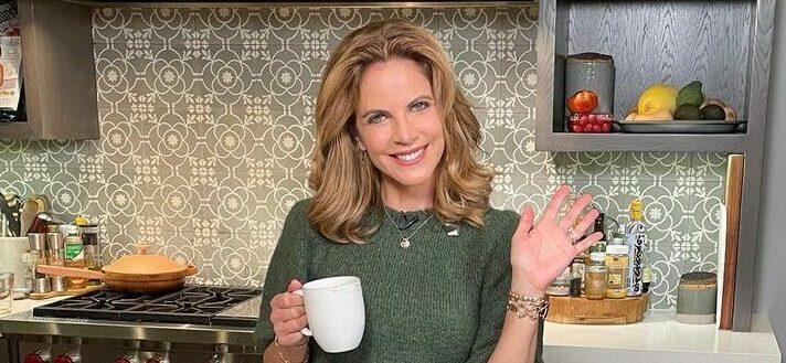 A lovely photo showing Natalie Morales in a T-shirt and denim pant holding a white mug.