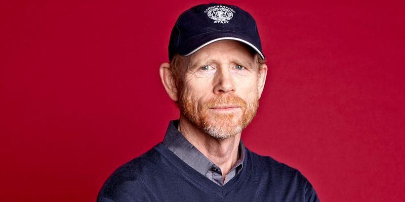 A photo showing Ron Howard sporting a blue sweater over a gray T-shirt and a sports cap to match