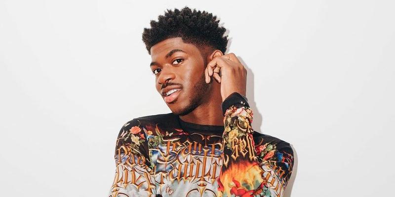 A photo showing Lil Nas X sporting a body hug multi colored outfit.