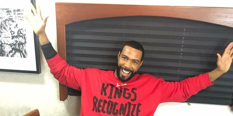 A photo showing Omari Hardwick in a red sweatshirt, with black imprints.