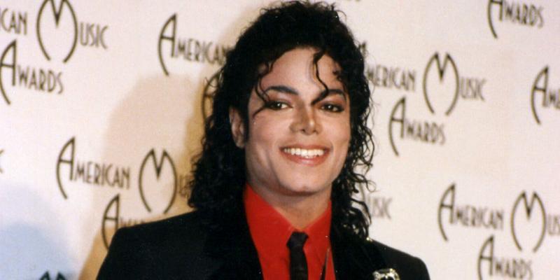 A photo showing Michael Jackson in his signature black suit paired with a red inner T-shirt at an event.