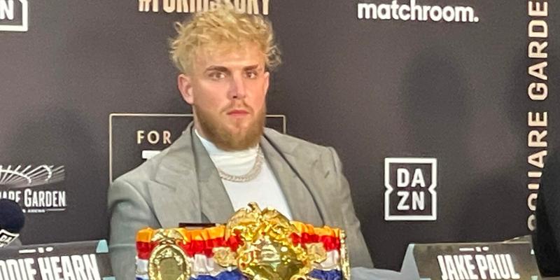 Jake Paul looks out at the media as he promotes the Taylor vs Serrano boxing event as his girlfriend sits in crowd nearby in NYC