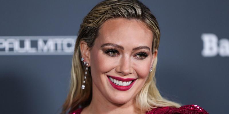 Hilary Duff wearing an Osman dress and Rahamoniv jewelry while wearing shoes and carrying a clutch by Jimmy Choo arrives at the Baby2Baby 10-Year Gala 2021