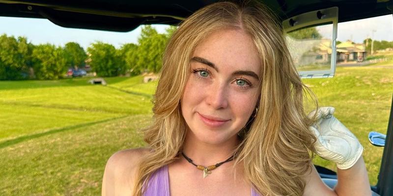 Grace Charis sits in a golf cart in a plunging purple crop top