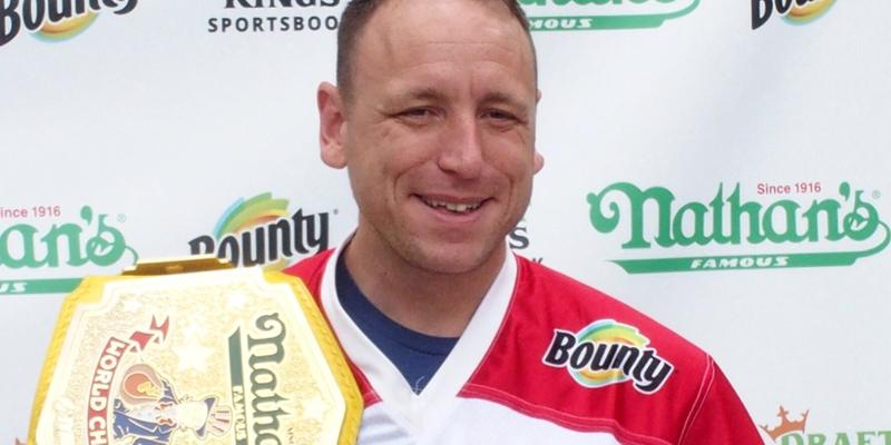 Joey Chestnut holding a plate of hot dogs at Nathan's July 4th Hot Dog Eating Contest 2021