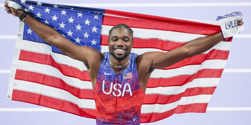 Noah Lyles celebrating at the 2024 Paris Olympics with American Flag