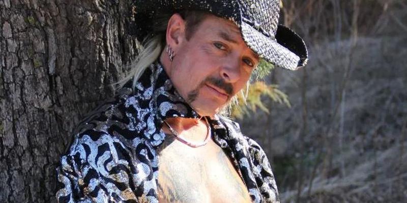 Joe Exotic striking a pose against a tree