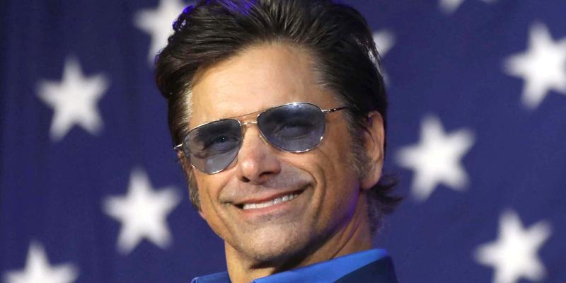 John Stamos stands in front of American flag