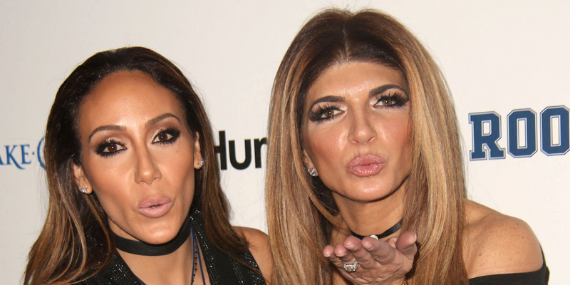 Teresa Giudice and Melissa Gorga posing next to each other and blowing kisses on the red carpet.