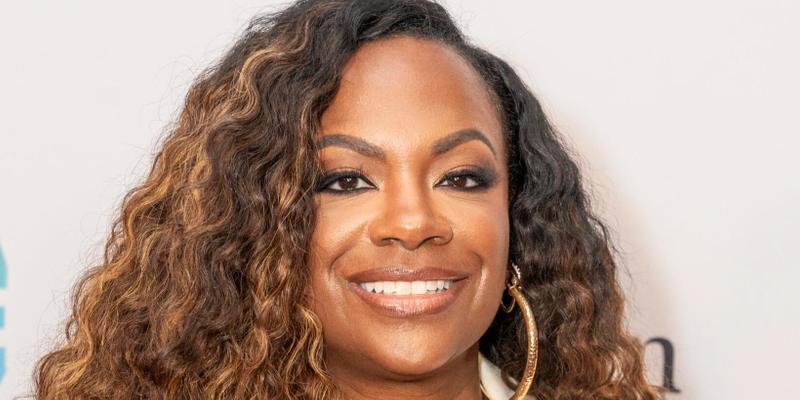 Kandi Burruss smiling while posing on the red carpet.