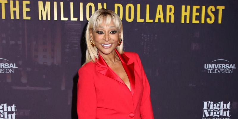 Karen Huger posing in a red dress on the red carpet.